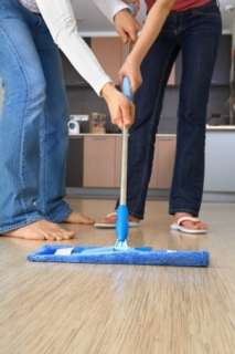 Happy couple cleaning a floor with blue microfiber mop